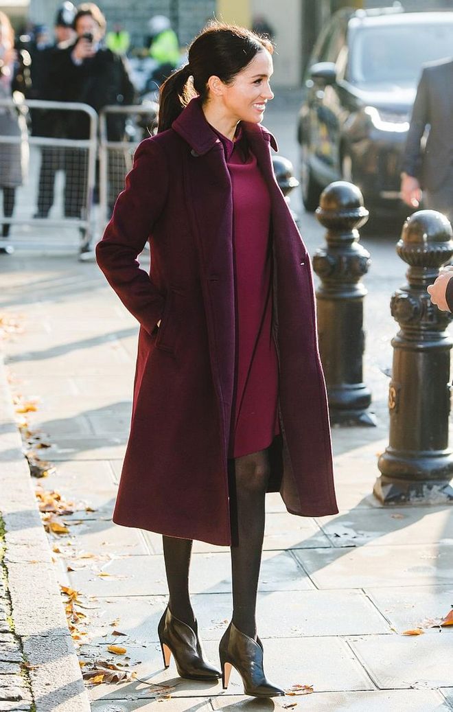 The Duchess of Sussex visits the Hubb Community Kitchen in a burgundy Club Monaco coat over their Sallyet dress in the same colour. She finished off the look with Givenchy 'GV3' black ankle boots. 