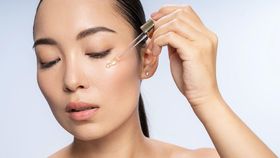 Close up of pretty lady putting anti-ageing moisturizing serum to under eye area. Beauty therapy concept