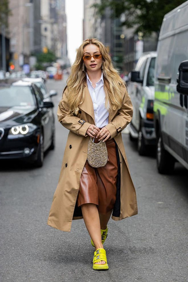 NEW YORK, NEW YORK - SEPTEMBER 09: Merve Görgöz wears brown trench coat, white button shirt, brown leather shorts, yellow sandals, sunglasses, bag outside Proenza Schouler on September 09, 2023 in New York City. (Photo by Christian Vierig/Getty Images)
