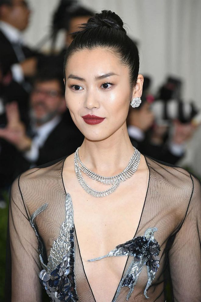 Liu Wen achieved a regal beauty look, enhancing her skin with blinding highlights to bring about a natural glow, and completes the look with her lips stained in a shade of deep plum (Photo: Getty)