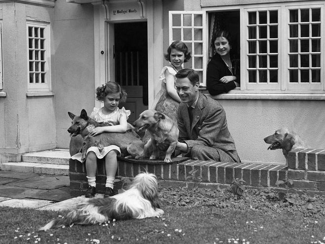 Then-Princess Elizabeth and Princess Margaret play with their family dogs alongside their parents, King George VI and Queen Elizabeth, in a miniature cottage on the grounds of Windsor Castle. The playhouse was gifted to Elizabeth by the people of Wales in 1931. Photo: Getty