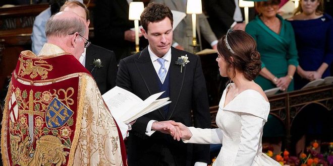 Princess Eugenie and Jack hold hands as they recite their vows at the alter.