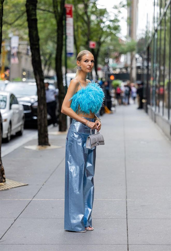  NEW YORK, NEW YORK - SEPTEMBER 14: Leonie Hanne wearing feathered blue top, blue metallic pants and a denim blue Small Hourglass Top Handle Bag from Balenciaga. (Photo by Christian Vierig/Getty Images)