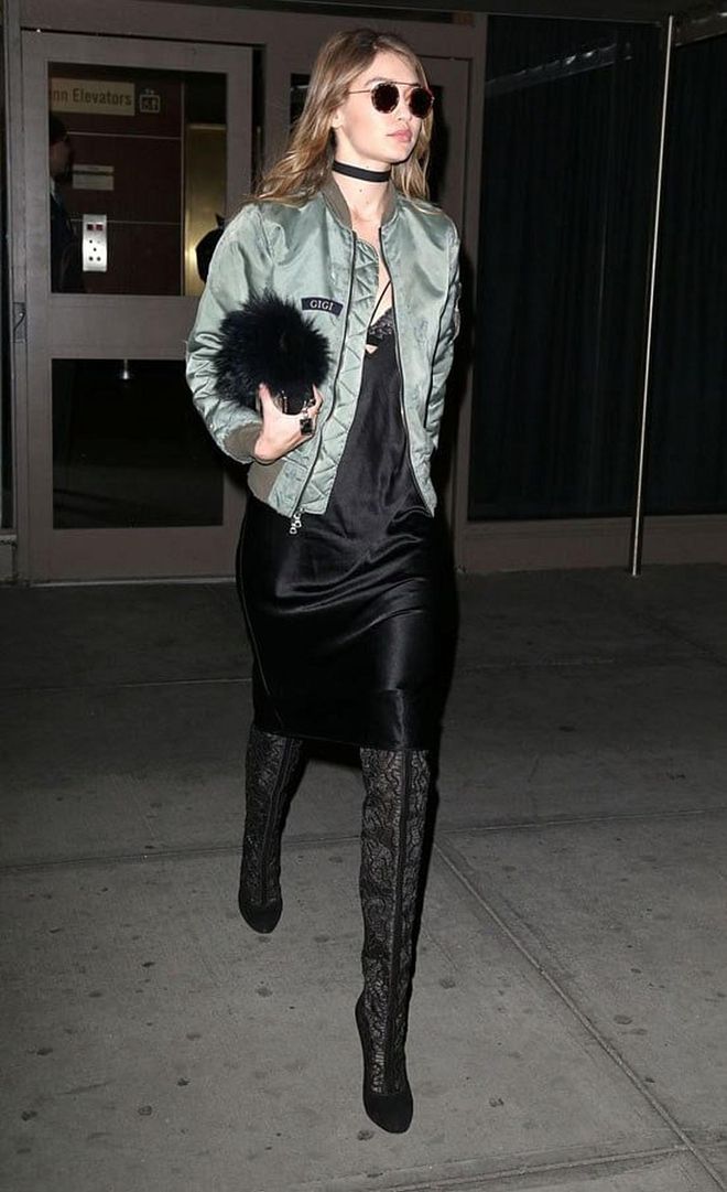 Hadid proves once again that she has mastered the bomber jacket. She stepped out in New York in a black slip dress, custom "Gigi" green bomber, lacy thigh high boots and choker.