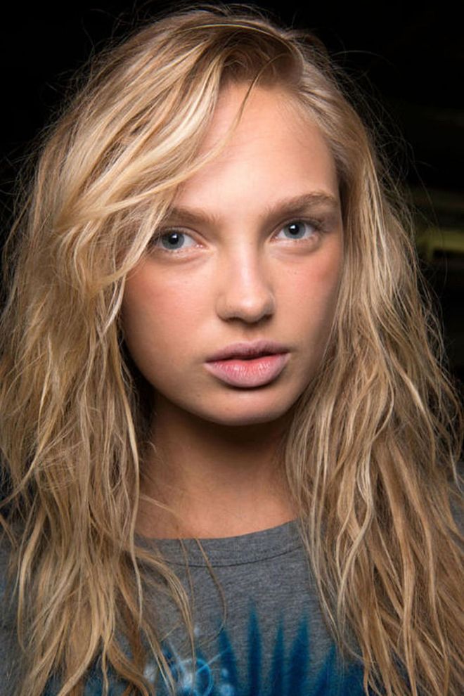 The Look: Beachy Everything
How-To: Models walked around in flip-flops and airbrushed tee shirts backstage at Alexander Wang, their hair rumpled and scrunched into salty waves. We weren't at the beach or boardwalk (though we were near the water) at New York's Pier 94 warehouse, yet the inspiration was clear: these were surfer girls, done in Alexander Wang's style. Makeup artist Diane Kendal left the makeup quite natural, except for a mix of Nars multiples in a matte brown and rosy shade that she applied on top of the cheeks. "It gives a natural, kind of dewy, sunkissed look," says Kendal. "It's like they've been outside and they're a little sunburnt. That's the idea." The hair was a more involved process. Hairstylist Guido Palau and his team bleached the hair of 18 models for the show and cut shaggy bobs on almost half.  The end result was a relaxed, surfer-boy beauty look that was undeniably cool. In other words, it was so very Alexander Wang. Photo: IMAXTREE