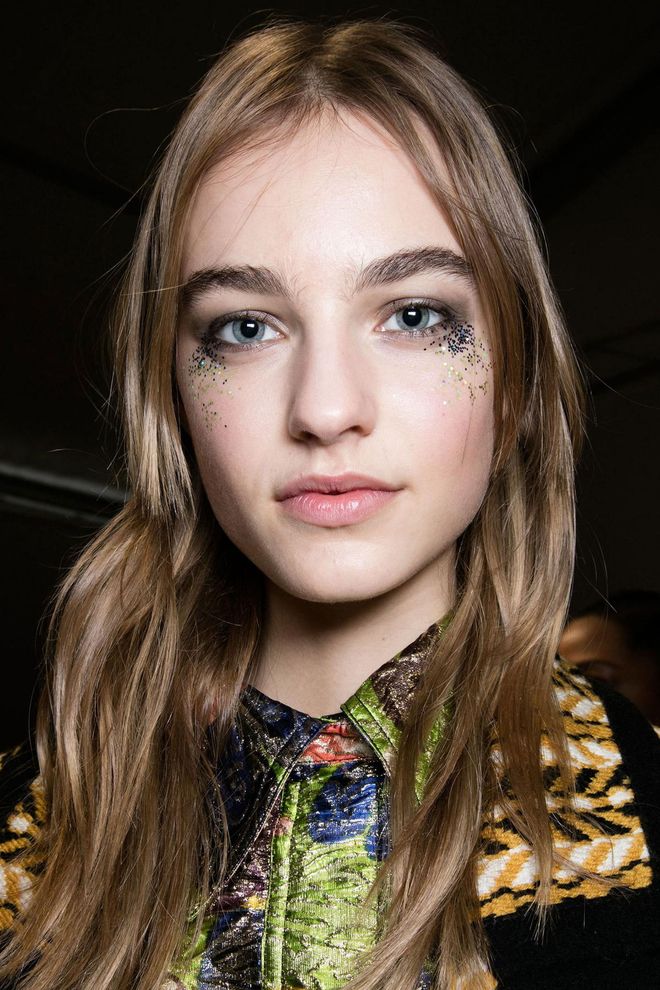 Inspired by the electric colors and metallic embroidery of the Fall collection, makeup artist Wendy Rowe and her team applied 3,000 glitter flecks under the eyes backstage at Burberry for a post-festival vibe.