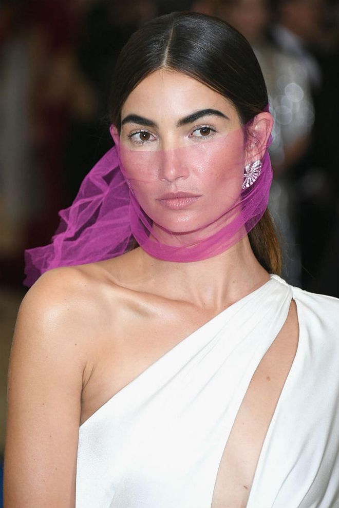 Aldridge keeps her makeup bare and simple, leaving the attention to her bold brows before completing the look with a sheer magenta veil (Photo: Getty)