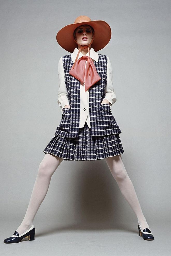 A model poses in a wide-brimmed orange leather hat, checkered coat, matching skirt, white coloured top. Photo: Getty 