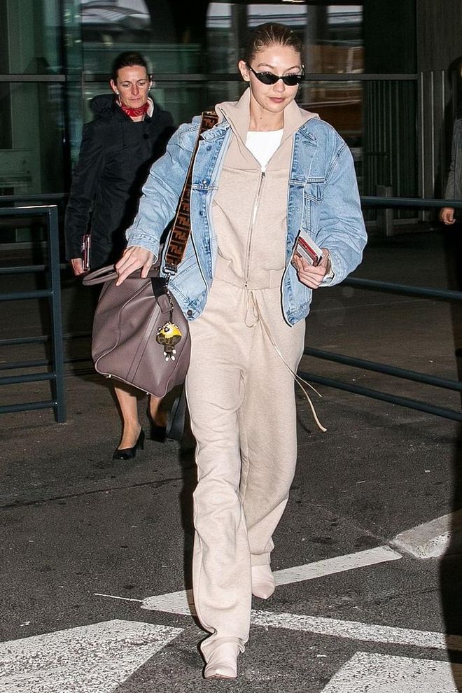 Gigi steps out of Charles-de-Gaulle airport in the chicest jumpsuit and denim jacket combo. 