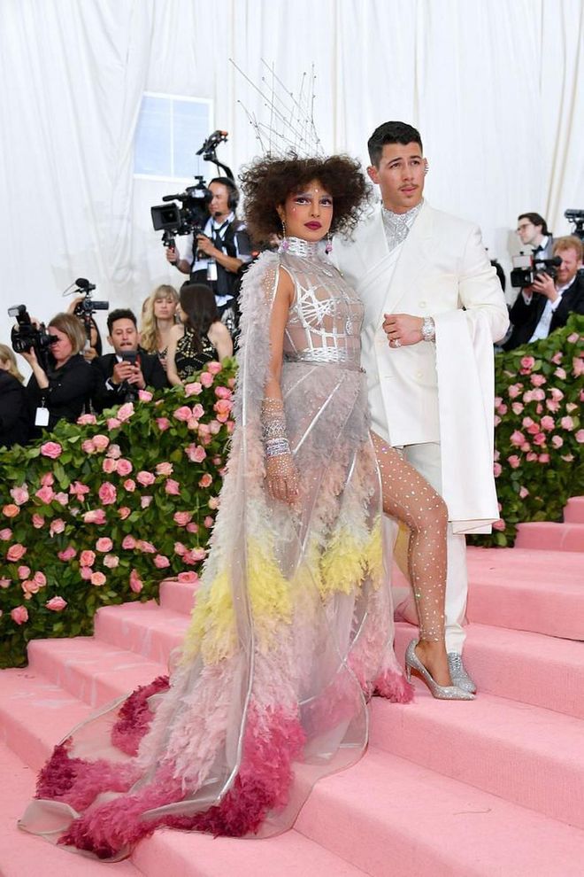 For their first Met Gala appearance as husband and wife, Priyanka stunned in a custom Dior gown featuring a silver caged bodice and yellow, pink, and grey ruffles.

Photo: Getty