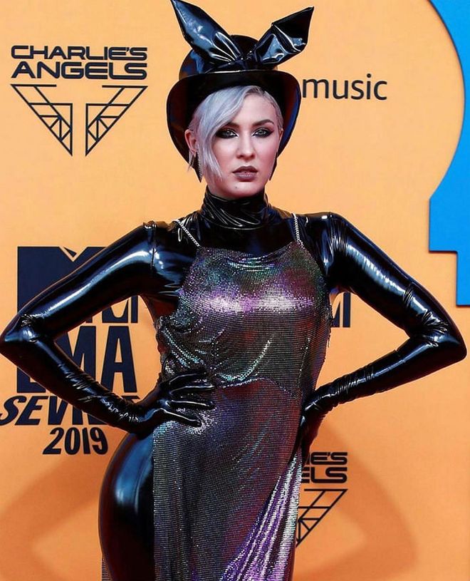 Maruv wears a playful black patent leather jumpsuit, top hat with bunny ears and a metallic slip dress.

Photo: Instagram