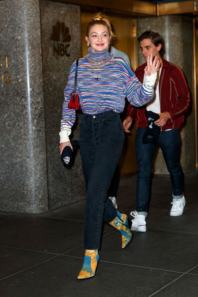 Gigi stepped out in a striped turtleneck sweater by JED, high-waist jeans, and blue and yellow tie-dye western boots after supporting Taylor Swift on SNL.