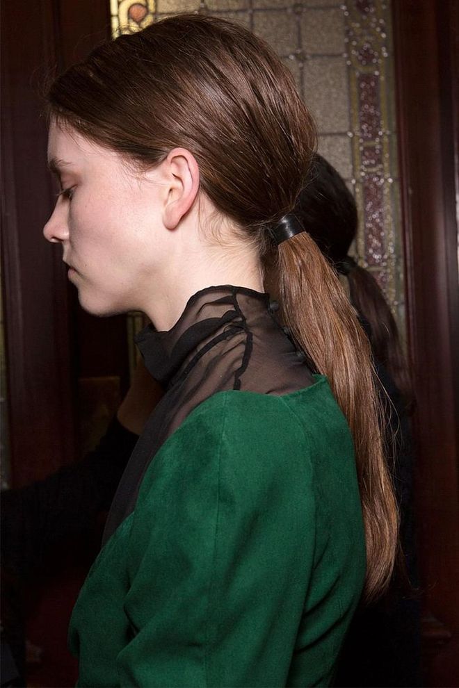 Rumpled low ponytails were held together by patent black string backstage at Olivier Theyskens.