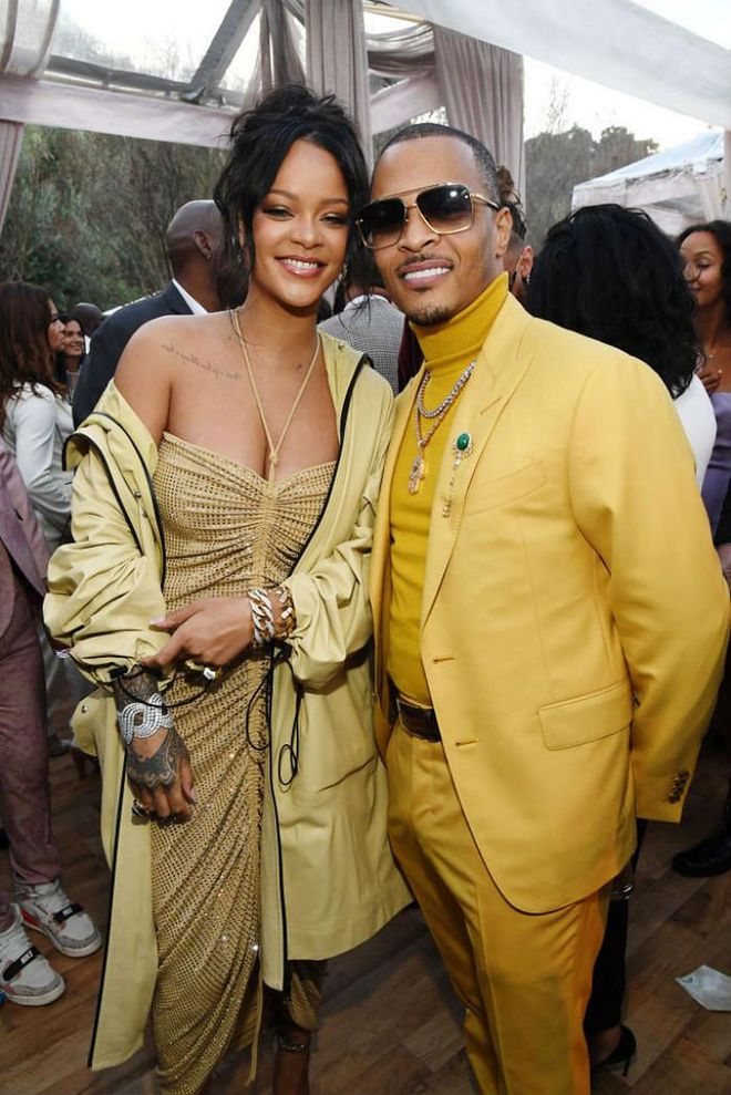 Rihanna stunned in a Bottega Veneta look at Roc Nation's The Brunch ahead of the Grammys. She donned a sparkly gold sequinned, ruched halter dress, which she paired with a matching oversized coat and accessorised with silver bling. Here, she strikes a pose with T.I.