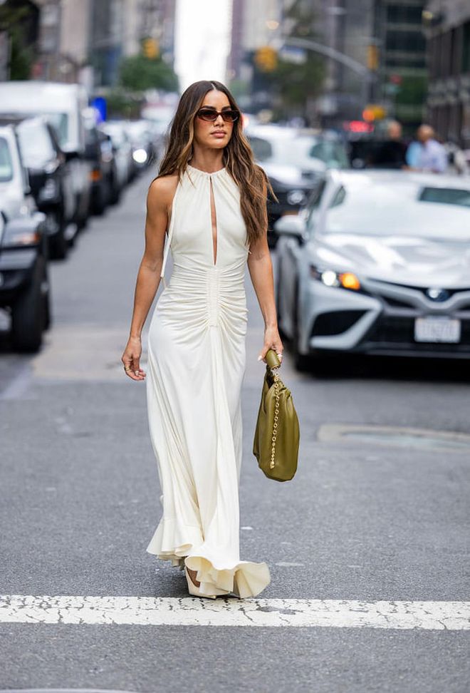 NEW YORK, NEW YORK - SEPTEMBER 09: Camila Coelho wears creme white dress with slit, green bag, sunglasses outside Proenza Schouler on September 09, 2023 in New York City. (Photo by Christian Vierig/Getty Images)