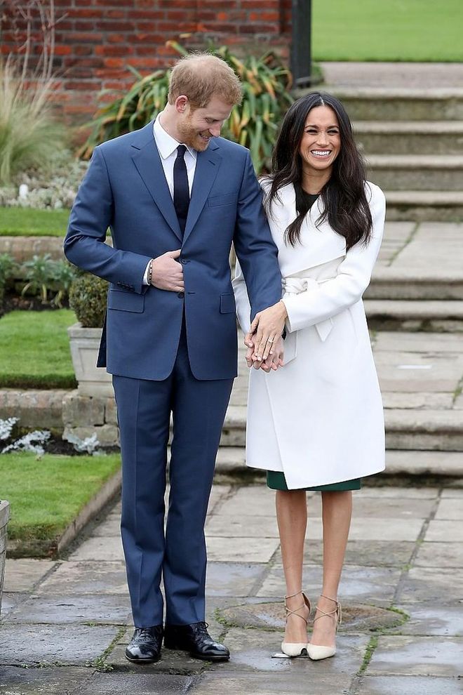 Wearing a simple white wrap coat paired with nude suede pumps from Aquazurra for the big engagement announcement. Underneath, Meghan chose a forest green dress from P.A.R.O.S.H. 