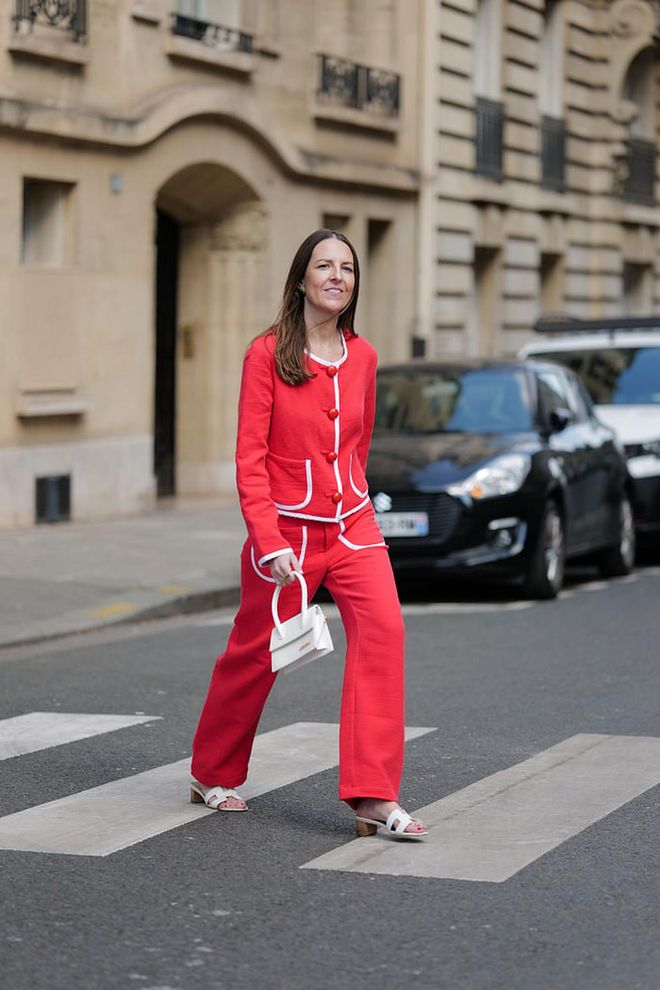 PARIS, FRANCE - APRIL 21: Alba Garavito Torre wears gold and green pattern earrings, a neon red embossed ribbed and white striped borders / large buttons jacket from La Veste x La Redoutte, matching neon red embossed striped print pattern large pants with white pockets pants from La Veste x La Redoutte , a white matte leather handbag from Jacquemus, gold rings, white shiny leather block heels Oasis sandals from Hermes, during a street style fashion photo session, on April 21, 2023 in Paris, France. (Photo by Edward Berthelot/Getty Images)