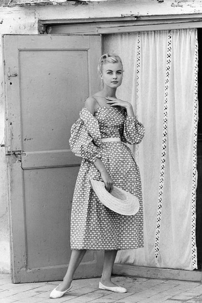A model shows off beach fashion in a print dress, ballet flats and a straw hat.

Photo: Getty