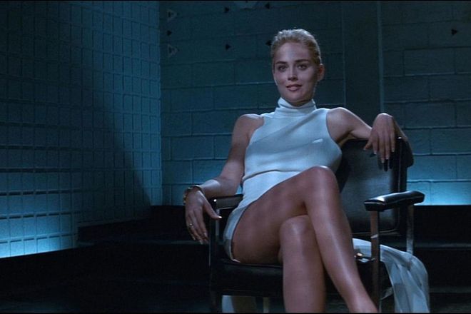 In one of the most famous scenes in Basic Instinct, Sharon Stone wears a sleeveless turtleneck dress made of winter white wool crepe. Costume designer Ellen Mirojnick made a choice to clothe Stone's femme fatale in pale neutrals instead of dark, vampy colors. Stone famously crosses and uncrosses her legs in the white dress, exposing her uncovered genitalia. (The actress later claimed this happened without her knowledge.) The graphic sexual nature of the scene (and the film) led to protest and criticism.
