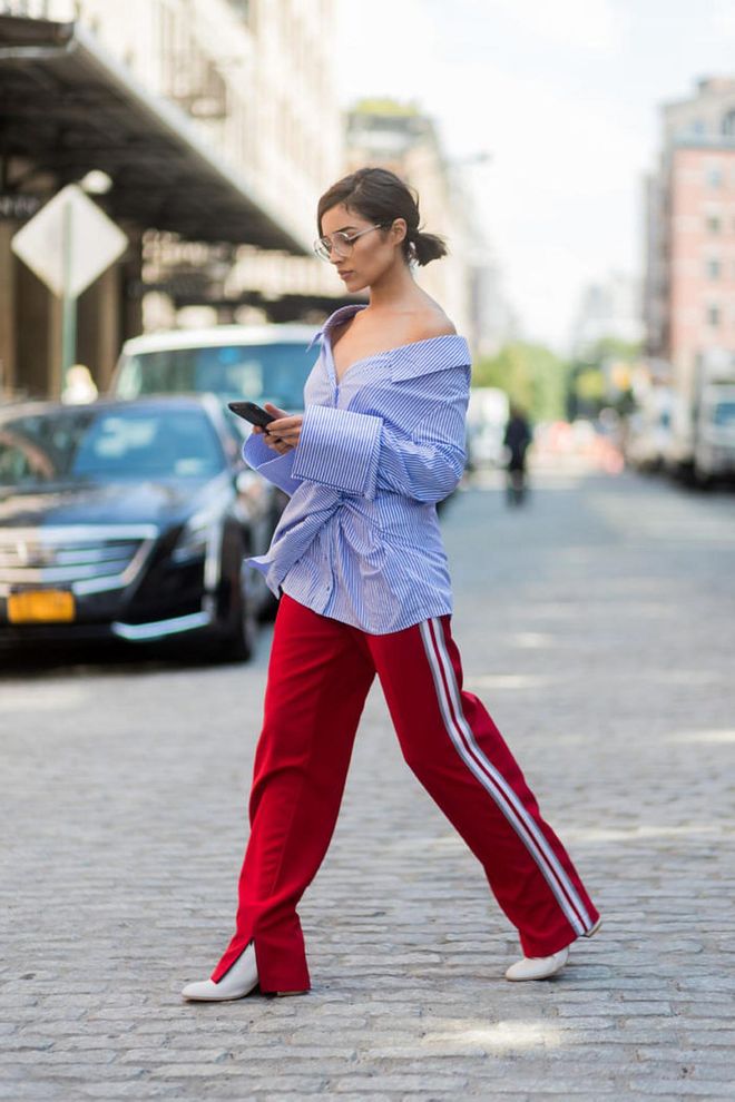 Olivia Culpo on the streets of Manhattan during New York Fashion Week wearing a blue white striped button shirt with long sleeves Off White, red pants Anderson bell, white boots Stuart Weitzman, Chloe glasses.
Photo: Getty