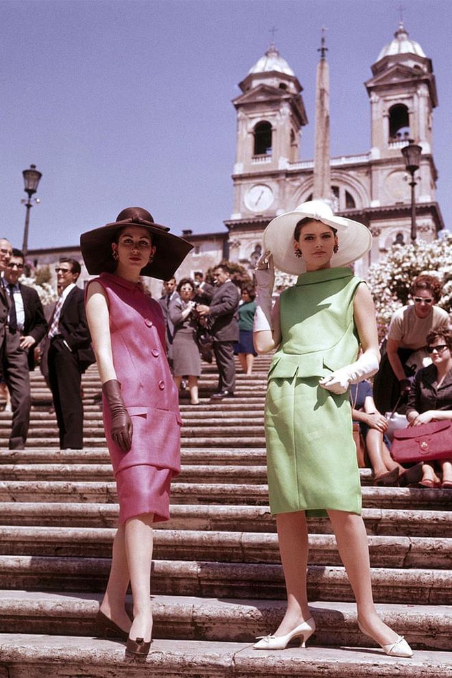 Two models in shift dresses, oversized hats and gloves on the steps of the Piazza di Spagna in Rome. Photo: Getty