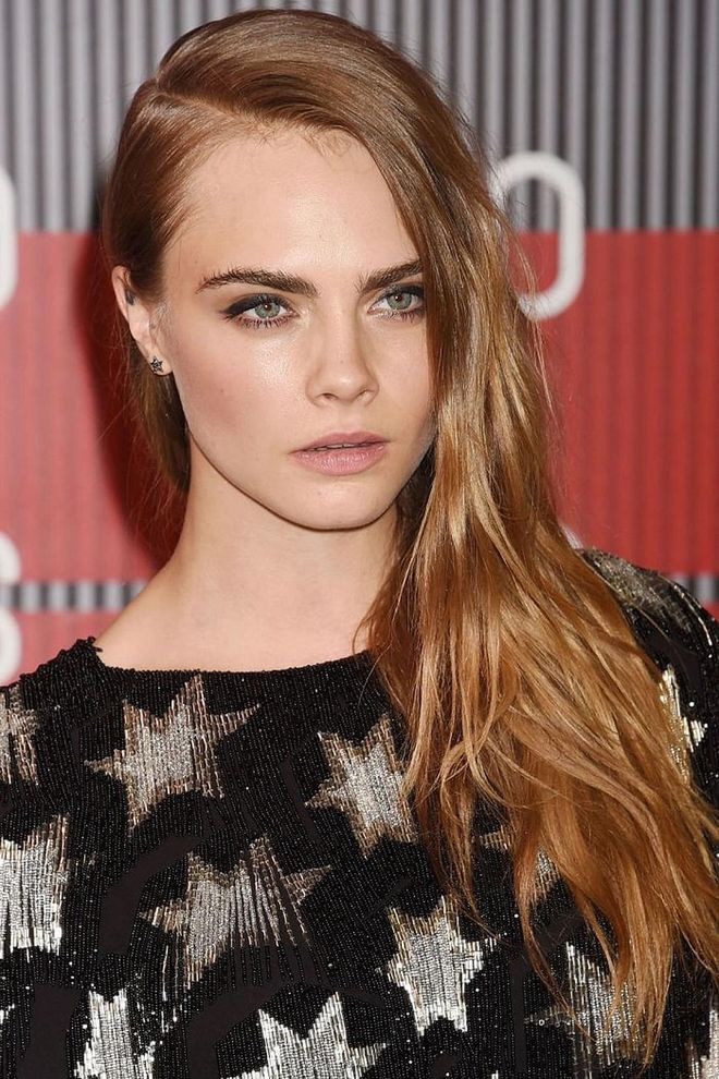 Strawberry blonde hair and a deep side part add dimension to Cara Delevingne's long hair. Photo: Getty 