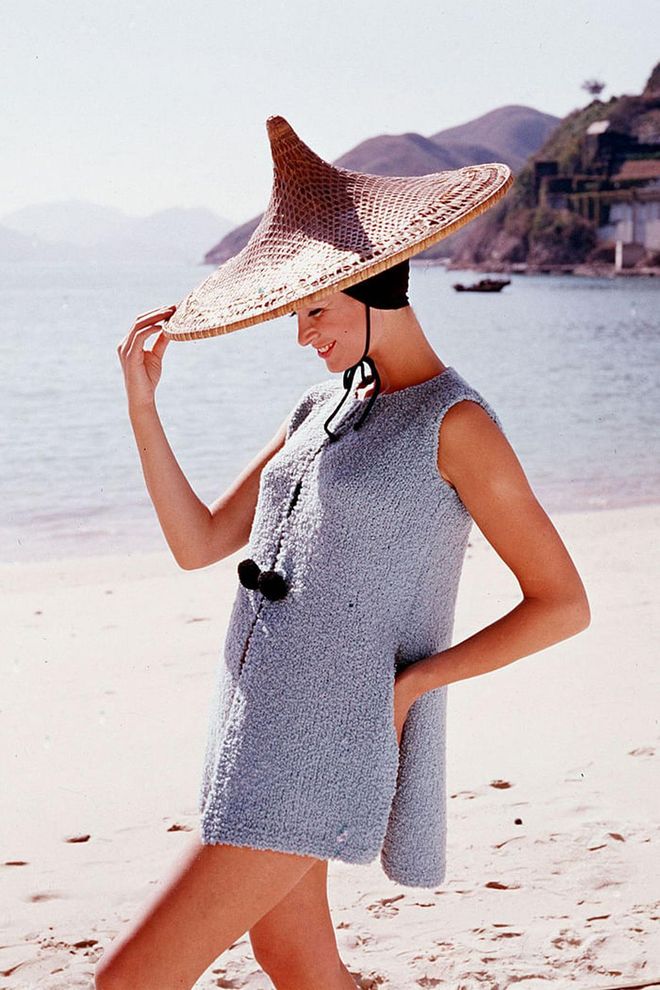 A woman wears an oversized straw hat and coverup on the beach. Photo: Getty 
