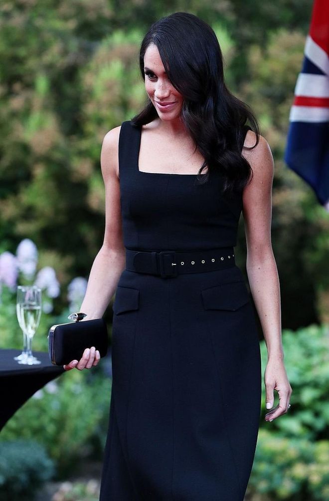 Meghan attended a Summer Party at the British Ambassador's residence in a black midi cocktail dress by Emilia Wickstead featuring a square neckline. She carried her little Givenchy satin clutch and Aquazzura Deneuve bow pumps in black. 
