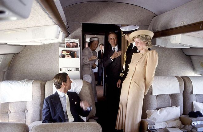 In a camel coat and hat while on a royal flight to Australia with Prince Charles and their staff. Photo: Getty