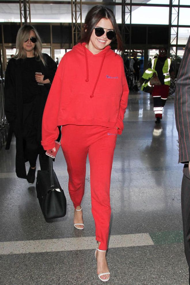 Selena Gomez made a statement at the airport as she teamed her red tracksuit with a pair of heeled sandals. Photo: Getty