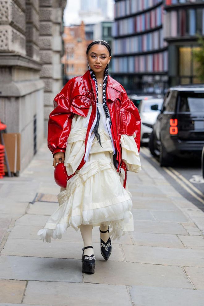 LONDON, ENGLAND - SEPTEMBER 18: Griff wears red vinyl jacket, creme white ruffled dress, black platform shoes outside Simone Rocha during London Fashion Week September 2022 on September 18, 2022 in London, England. (Photo by Christian Vierig/Getty Images)
