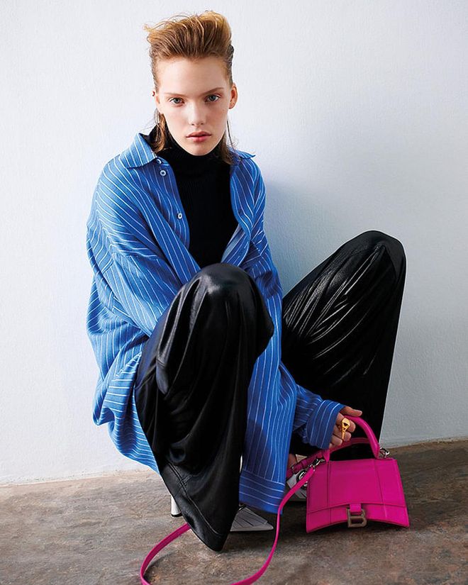 Hourglass top handle XS bag in acid fuchsia. Knit shirt; cotton and cashmere ribbed knit turtleneck; laminated jersey oversize pants; leather pumps, Paris Eiffel Tower ring.