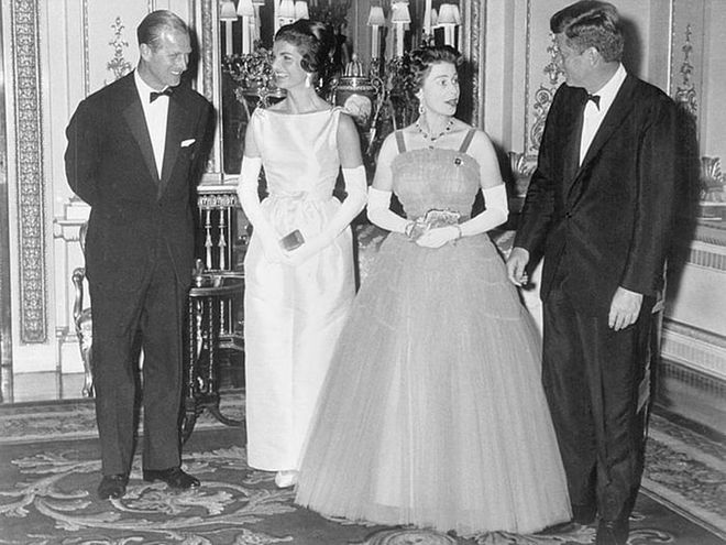 Prince Philip, former First Lady Jackie Kennedy, Queen Elizabeth, and former President John F. Kennedy attend dinner at Buckingham Palace.