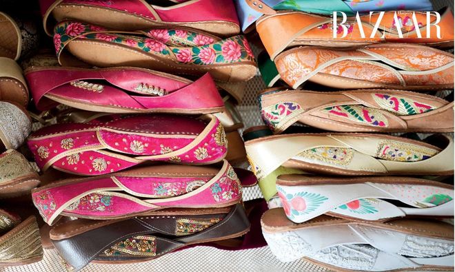 A drawer containing three layers of handcrafted khussas (traditional embroidered Pakistani shoes) arranged by their colours