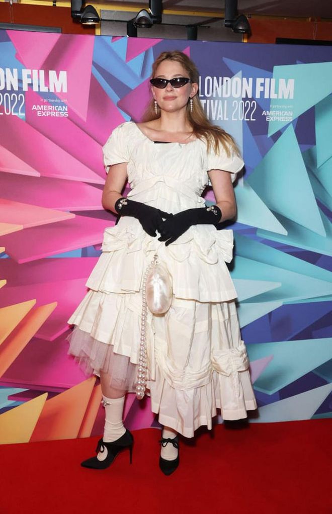 Haley Bennett in a Simone Rocha look, including beaded socks and opera gloves and an egg-like purse.