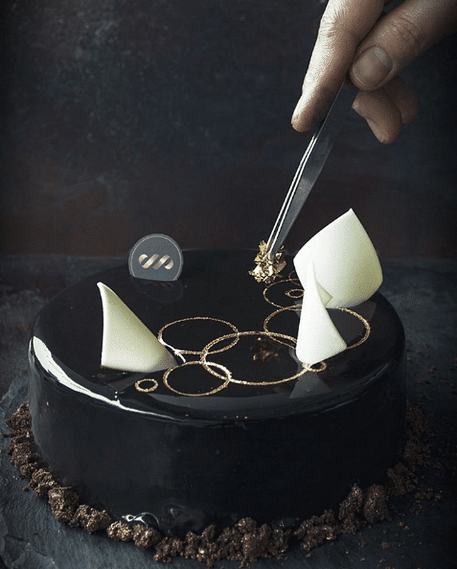 <<b>We recommend:</b> The Naomi. A rich, multi-layered chocolate fudge cake finished off with a glistening black-as-night glaze and a welcome sprinkling of fudge cookies for added texture. Photo: Instagram (@pulsepatisserie)
