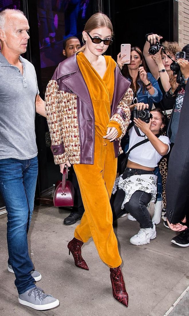Leaving the Oscar De La Renta SS19 Fashion Show in a canary yellow velvet jumpsuit with sa purple patterned coat and burgundy python booties. 