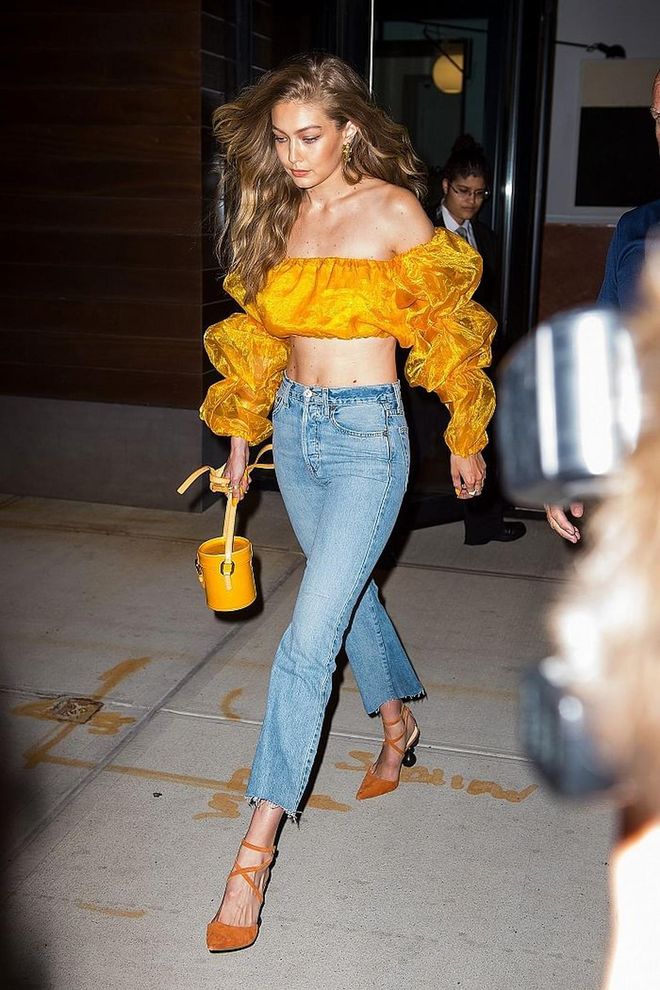 Gigi is a summer goddess in this sunshine yellow off-shoulder top by Slashed by Tia, matched with a yellow Louis Vuitton bucket bag. 