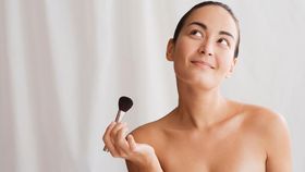 Mixed race woman holding makeup brush and looking up