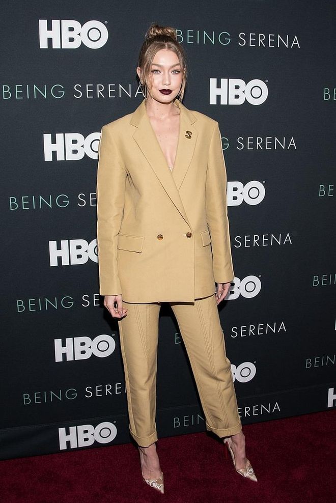 In a double-breasted beige suit by Derek Lam, with nothing underneath, naturally. She pairs it with Louboutin LoubiKraft pumps and a vampy lip. 
