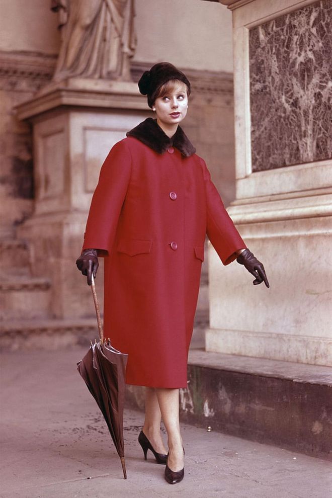 A woman wears a red, fur-coloured cot with with brown leather gloves and matching pumps. Photo: Getty 
