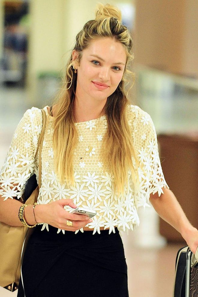 Candice Swanepoel's Rapunzel-length hair is offset by a sky-high bun and loose face-framing tendrils. Photo: Getty