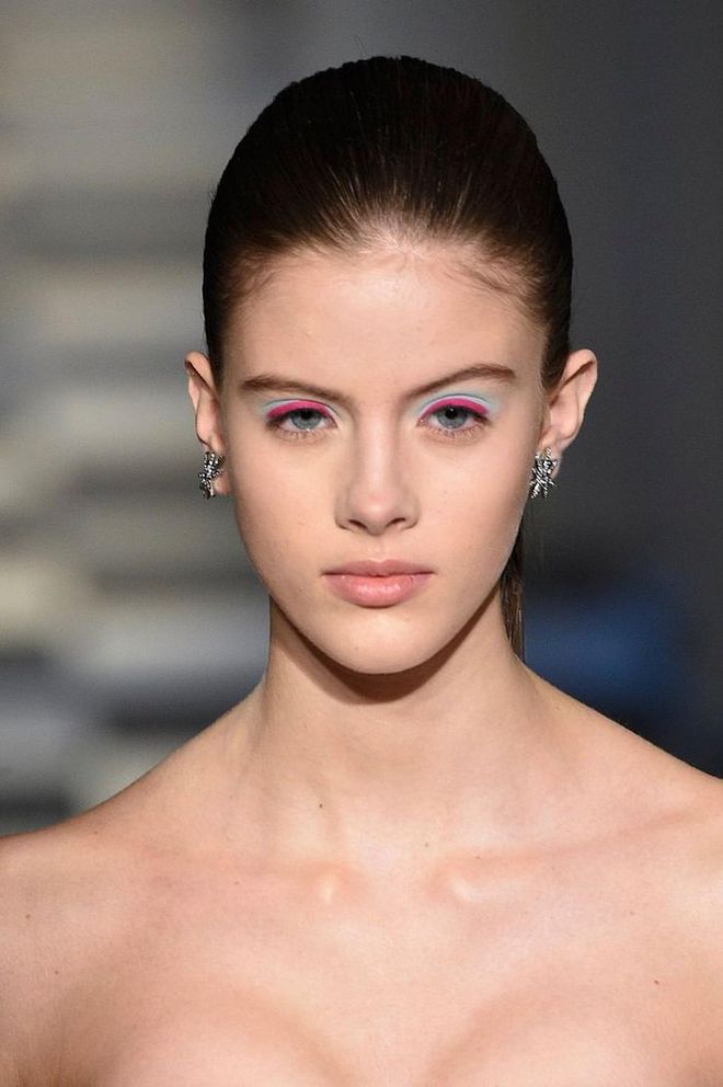 Oscar De La Renta's feminine yet structured silhouettes are accented with this pink and blue graphic eye look and ultra sleek ponytails. The tops lashline is lined with bright fuschia and a baby shadow is blown out underneath. Photo: Getty 