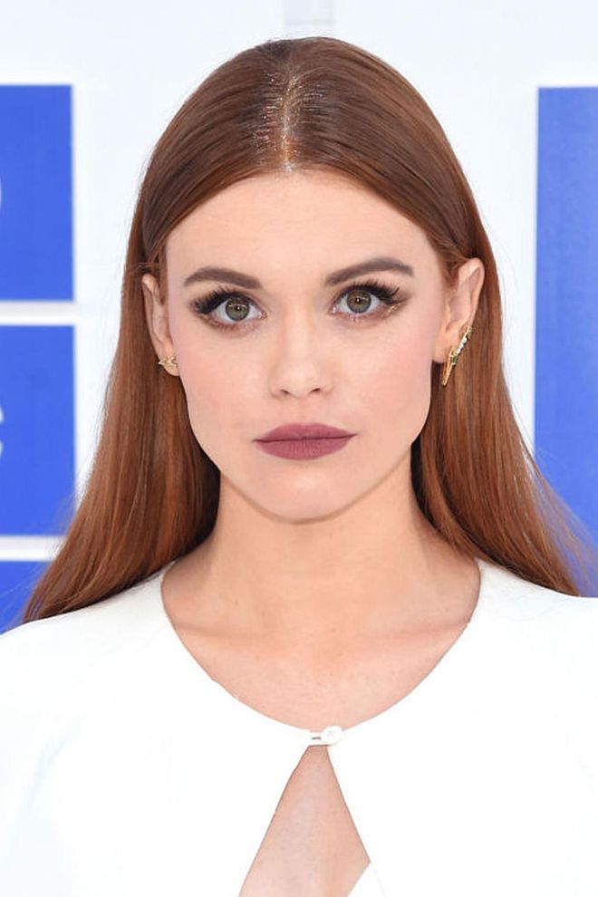 The Teen Wolf star accents her middle part with gold glitter while donning a moody purple lip. 